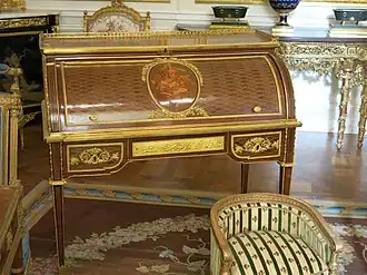 Louis XVI style roll-top desk of Marie-Antoinette; by Jean-Henri Riesener; 1784; oak and pine frame, sycamore, amaranth and rosewood veneer, bronze gilt; 103.6 x 113.4 cm; Louvre[63]