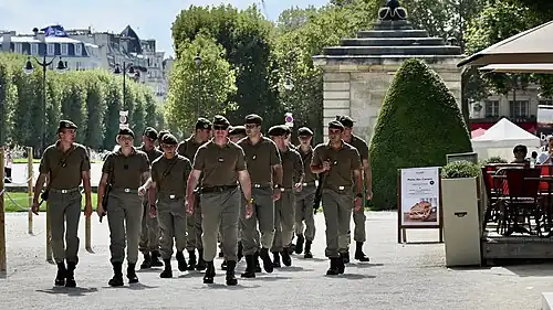 A group of soldiers is walking down a park street