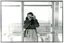 Dona Ann McAdams holds up a Leica camera while taking a self-portrait at the Empire State Building