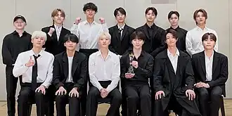 The thirteen members of Seventeen with an award