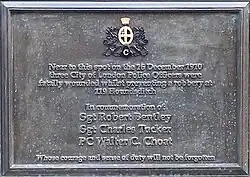 Oblong, brown plaque bearing the words "Near to this spot on the 16 December 1910 three City of London Police Officers were fatally wounded whilst preventing a robbery at 199 Houndsditch. In commemoration of Sgt Robert Bentley, Sgt Charles Tucker, PC Walter C Choat whose courage and sense of duty will not be forgotten."