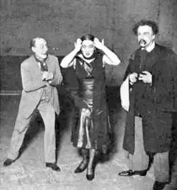 Manager with stepdaughter gesticulating in a distraught manner while the father looks bemused