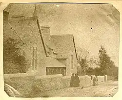 Black-and-white photograph of a small group of women and children stood outside a school building.