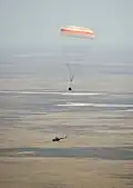 The Soyuz TMA-03M capsule descends past helicopter.