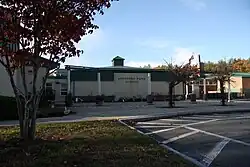 This image depicts the front facade of Spofford Pond School, which is white brick with a green metal roof.