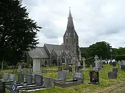 A medium-sized church with a tall stone steeple in a graveyard.