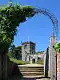 Part of a battlemented church and tower seen through an archway