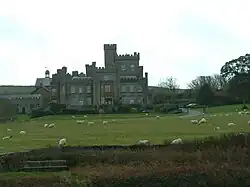 a castellated house viewed cross a field with sheep