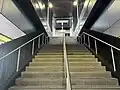 The staircase from the mid-level concourse leading up to the platforms, July 2024