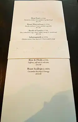 A rectangular menu that includes the dishes of the day and their respective costs.