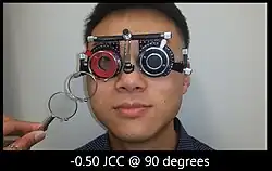 a patient wearing trial frame while doing test for astigmatism