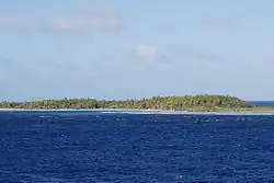 Vegetated green island rising from above the deep blue sea
