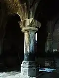 One of the columns of the gavit. The grave of Princess Khatun lays covered with a white cloth behind.