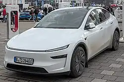 A front three-quarters view of a white 2025 facelifted Tesla Model Y