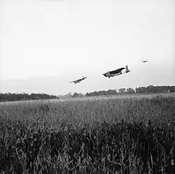 Large gliders in the sky, preparing to land in a field