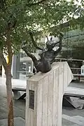 a bronze statue of a girl, arms and legs extended, sliding downwards on a 30-degree slope