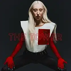 The cover artwork for "The Tower". The cover features Luna in a red and white outfit amongst a grey background. In the middle of the image, the words "The Tower" in red are printed.