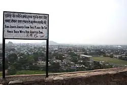 A sign on a wall looking out onto a town