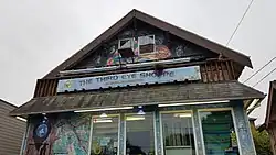 Photograph of a building's exterior, which is covered in colorful murals and has a sign displaying "The Third Eye Shoppe" in the center