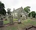 A severe, grey single-storey chapel with Georgian windows and small bellcote. The churchyard has lines of headstones in neat rows.