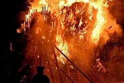 Burning tree shaped structure at night.