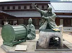 Sculptures of a drummer and a person on a water outlet.