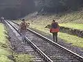 Track workers walking the line through the old station with the tunnel beyond