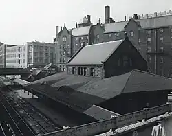 A stone Romanesque railway station with a wide canopy in an urban area