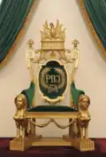 Imperial cypher of Emperor Pedro II of Brazil on his throne. The "J" represents the capital i, for Imperador, the Portuguese word for emperor