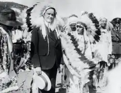 President Coolidge stands with a Native American. Both wear traditional feather headdresses.
