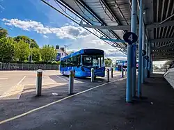 A two-tone blue single deck bus parked in an empty bus station.
