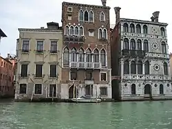 A row of three waterside Venetian buildings, having between three and five stories, with contrasting arrangements of arcades, windows and balconies.