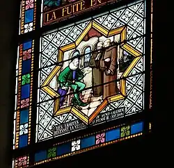 Color photograph of a stained glass window depicting a seated figure in front of monks.