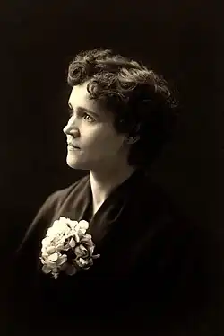 Portrait photograph of Voltairine de Cleyre, wearing a kimono with a flowery brooch and short, curly hair