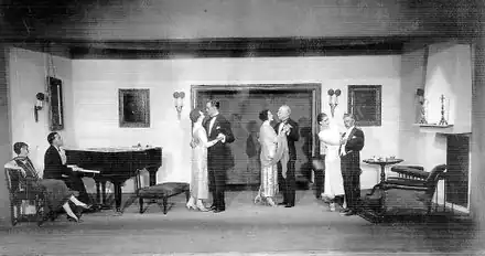 large room with young man at a grand piano accompanying three dancing couples