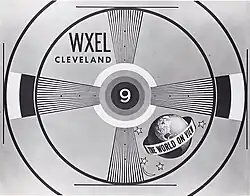 Television text pattern slide in the monochrome "bullseye" test style. Inside the center is a numeric "9"; at top-left in two lines are "WXEL" and "CLEVELAND"; at bottom-right is a globe with a band in the middle, reading "THE WORLD ON VIEW"