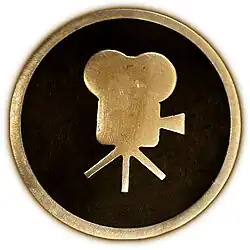 Circular 4-inch brass plaque showing a side view of a classic movie camera.