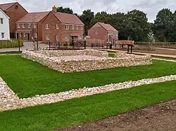 Low walls of flint creating an inner square chamber surrounded by an outer chamber