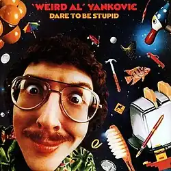 The cover for Dare to Be Stupid features "Weird Al" Yankovic's face against a backdrop of space. Scattered around his head are various items, such as a fish, a toaster, a toothbrush, and a hammer.