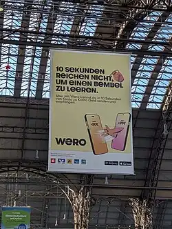 Text: 10 Sekunden reichen nicht, um einen Bembel zu leeren. Aber mit Wero kannst du in 10 Sekunden von Konto zu Konto Geld senden und empfangen. (Translation: 10 seconds is not enough to empty a bembel. But with Wero you can send and receive money from account to account in 10 seconds). [Illustration of two phones with a rocket flying between them, one phone with the balance of minus €20 and the other €20 plus, logo of Wero, logos of supported banks, and download badges for Google Play and Apple App Store]