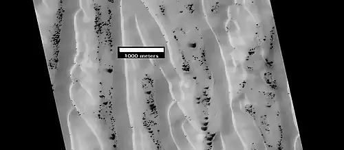 Dunes and defrosting spots in Richardson Crater, as seen by HiRISE. It is thought that films of liquid water sometimes exist in and around the dark spots.