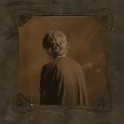 A sepia-toned image of a young man from behind