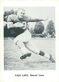 Trading card image of Yale Lary doing the Heisman pose with a ball in one arm and no helmet.